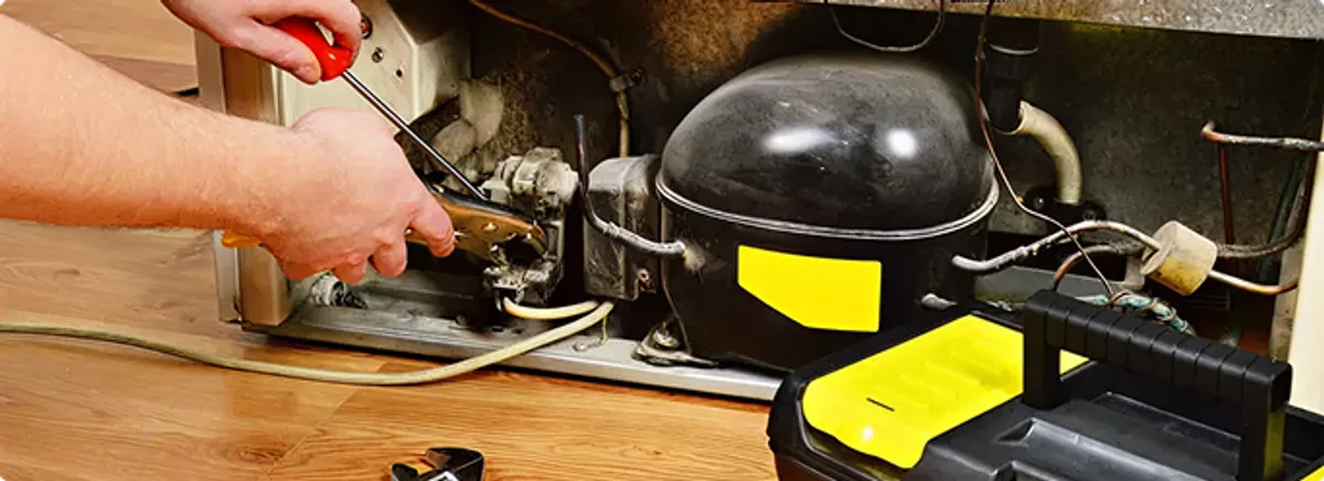 Refrigerator repair technician fixing the compressor and wiring in Stilwell, KS