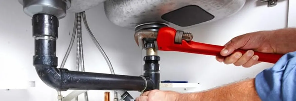 Garbage disposal repair technician tightening the sink drain and disposal connection in Overland Park, KS